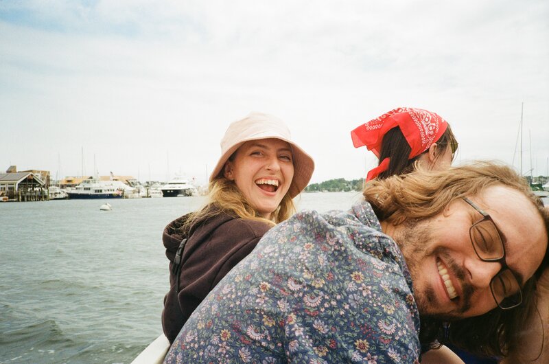 Three friends smiling and laughing on a boat in the harbor of Newport Ri