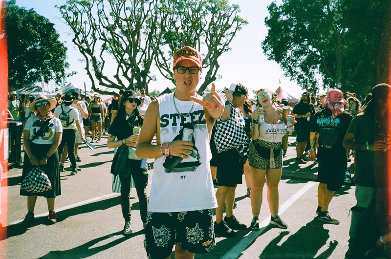 A man holding up the rock horns at a concert surrounded by people in Los Angeles, CA.