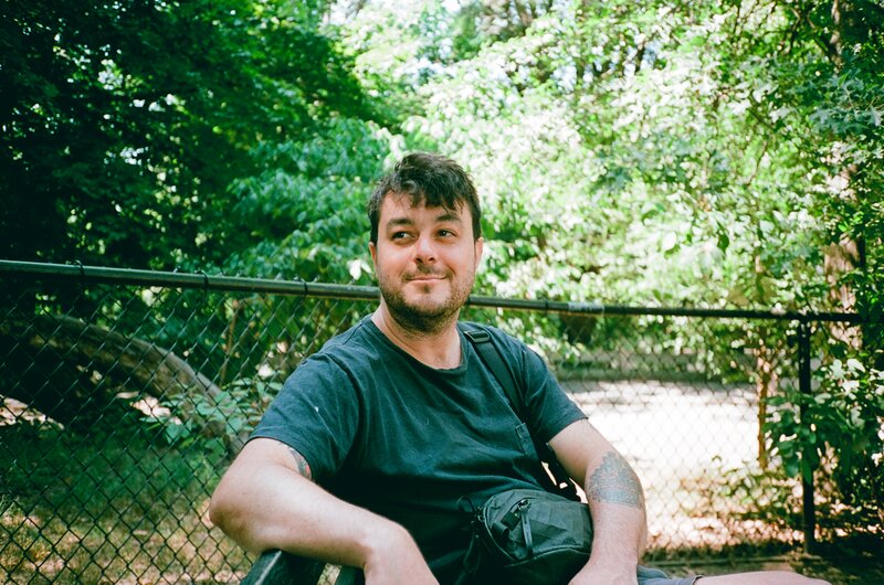 A man sitting on a bench at the dog park in Brooklyn, NY.